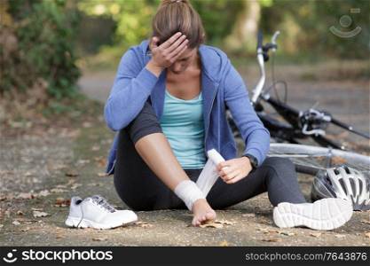 woman bandaging knee after falling from bicycle