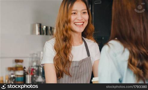 Woman barista, waitress showing gesture with menu and talking to customer at cafe restaurant. Beautiful young Korean girl order food across bar counter at coffee shop. Owner small business concept.