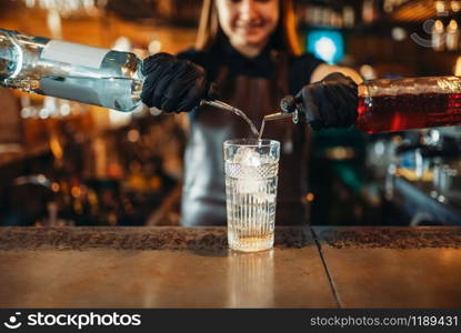 Woman bartender mixing alcoholic coctail. Alcohol drink preparation. Female barman working at the bar counter in pub. Woman bartender mixing alcoholic coctail in pub