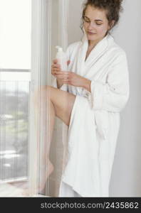 woman bathrobe applying lotion