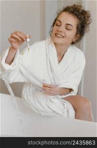 woman bathrobe pouring serum bathtub 2