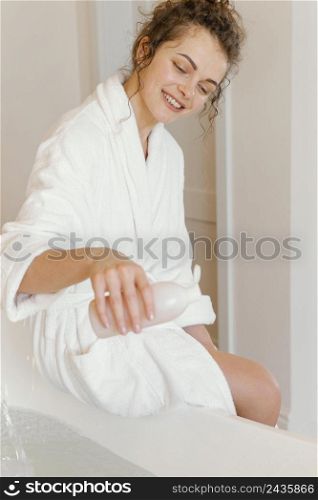 woman bathrobe pouring soap bathtub