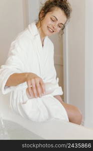 woman bathrobe pouring soap bathtub