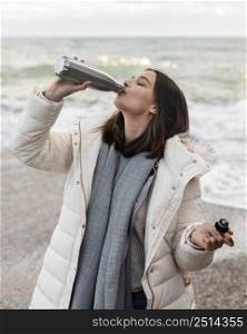 woman beach having drink from bottle