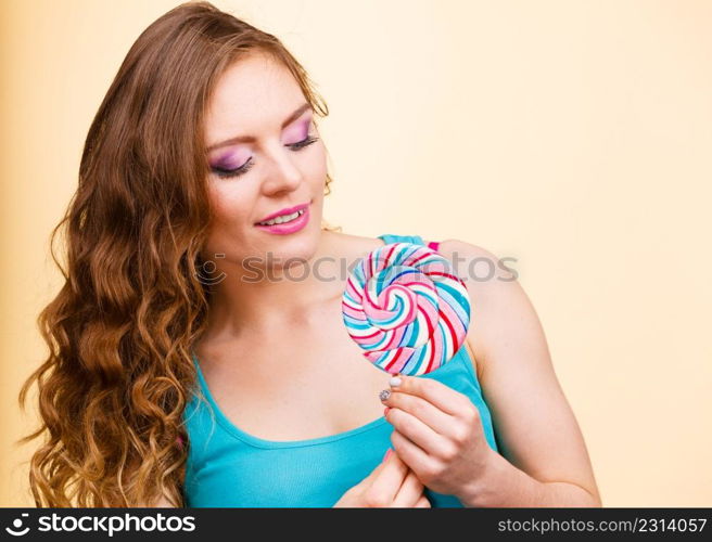 Woman beautiful cheerful girl holding colorful lollipop candy in hand having fun. Sweet food and happiness concept. Studio shot on bright background. Woman joyful girl with lollipop candy