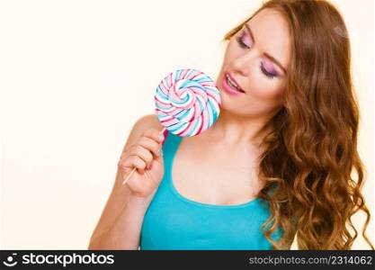 Woman beautiful cheerful girl holding colorful lollipop candy in hand having fun. Sweet food and happiness concept. Studio shot on bright background. Woman joyful girl with lollipop candy