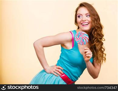 Woman beautiful cheerful girl holding colorful lollipop candy in hand having fun. Sweet food and happiness concept. Studio shot on bright background. Woman joyful girl with lollipop candy