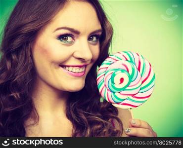 Woman beautiful cheerful girl holding colorful lollipop candy in hand. Sweet food and happiness concept. Studio shot vivid color green background, toned image