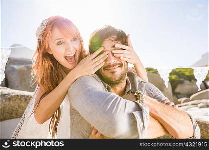 Woman behind man covering his eyes with hands smiling