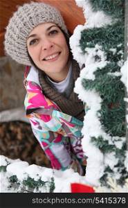 Woman behind snowy tree