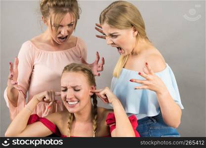 Woman being bullied by her two female friends. Women having argument. Angry fury girls screaming at her friend or younger sister. Friendship difficulties, rivaly and envy problems.. Woman being bullied by two females