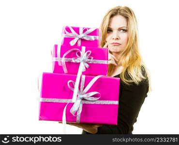 Woman being confused by amount of gifts she received. Female having weirdly surprised face expression holding big stack of presents.. Confused woman holding gifts