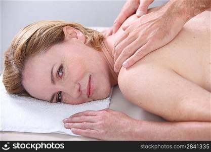 Woman being given a back massage and looking at us.