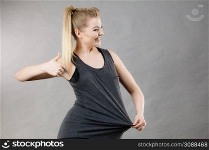 Woman being surprised after huge weight loss, her t shirt is to big. Dieting and workout effects concept.. Woman wearing too big tshirt