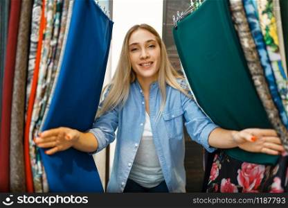 Woman between fabric in textile store. Seamstress choosing material for sewing, female tailor in shop, dressmaker. Woman between fabric in textile store