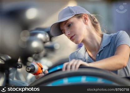 woman bicycle mechanic is repairing a bike outdoors