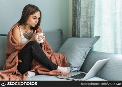 woman blanket having coffee home working laptop during pandemic