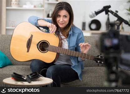 woman blogger repairing strings on an acoustic guitar