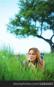 woman blow on dandelion on green field under tree