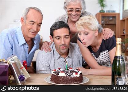 woman blowing birthday candles in family