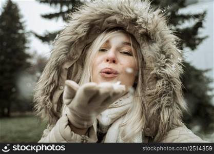 woman blowing into snow from her hand