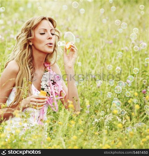 Woman blows soap bubbles on flower field