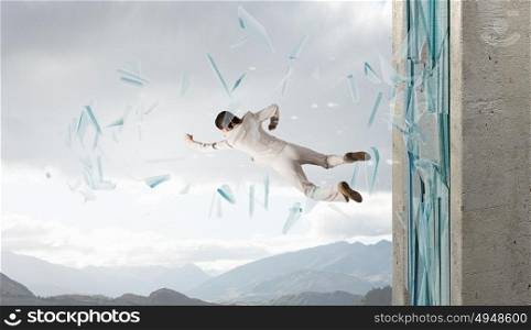 Woman breaking through glass. Young determined businesswoman breaking glass with karate punch