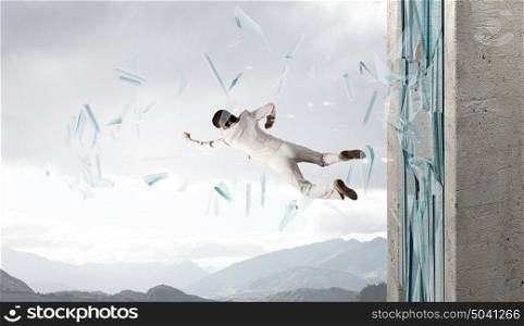 Woman breaking through glass. Young determined businesswoman breaking glass with karate punch