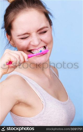 Woman brushing cleaning teeth. Girl with toothbrush. Oral hygiene. Blue background. Woman brushing cleaning teeth