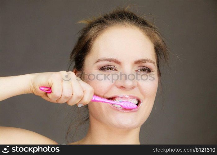 Woman brushing cleaning teeth. Girl with toothbrush. Oral hygiene. Dark background. Woman brushing cleaning teeth