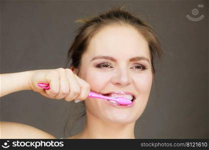 Woman brushing cleaning teeth. Girl with toothbrush. Oral hygiene. Dark background. Woman brushing cleaning teeth