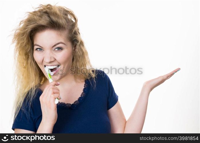 Woman brushing cleaning teeth. Positive girl with toothbrush holding open hand copy space for product. Oral hygiene.. Woman brushing teeth holds open hand