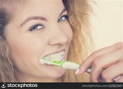 Woman brushing cleaning teeth. Positive girl with toothbrush. Oral hygiene. Toned image. Woman brushing cleaning teeth