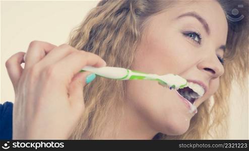Woman brushing cleaning teeth. Positive girl with toothbrush. Oral hygiene. Toned image. Woman brushing cleaning teeth