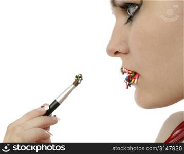 Woman brushing on lipstick made of candy. Focus in mirror.