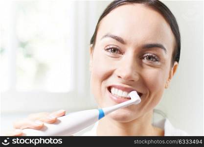 Woman Brushing Teeth With Electric Toothbrush In Bathroom