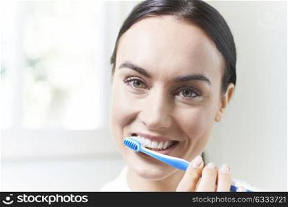 Woman Brushing Teeth With Toothbrush In Bathroom