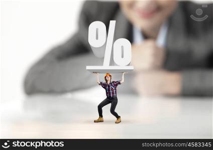 Woman builder. Businesswoman looking at miniature of builder holding percentage sign