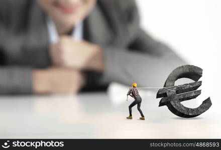 Woman builder. Businesswoman looking at miniature of builder pulling euro sign