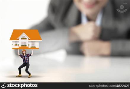 Woman builder. Businesswoman looking at miniature of woman builder holding model house