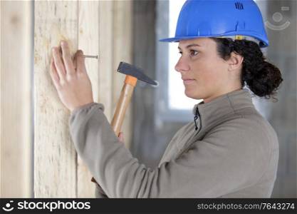 woman builder hammering a wall