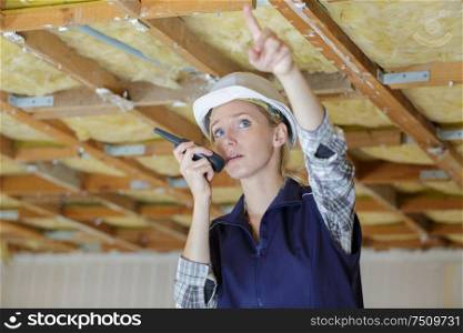 woman builder in protective clothes at construction site walkie-talkie