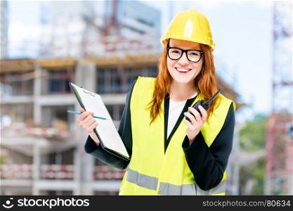 Woman builder in protective clothes at construction site walkie-talkie
