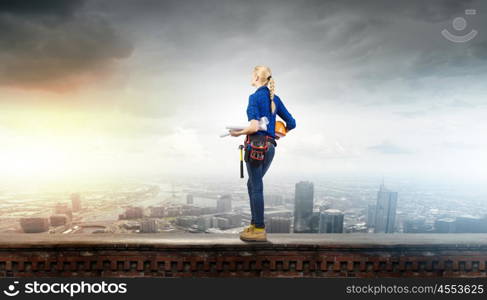 Woman builder. Rear view of woman builder with hardhat and papers in hands