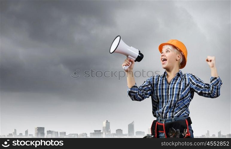 Woman builder with megaphone. Young emotional woman builder screaming in megaphone