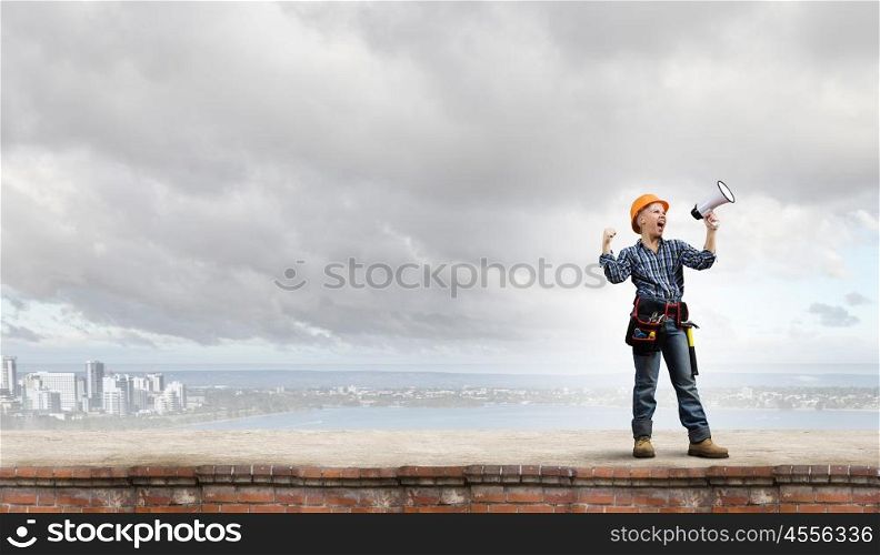 Woman builder with megaphone. Young emotional woman builder screaming in megaphone