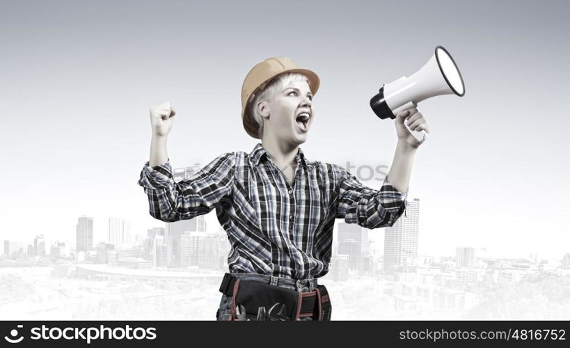 Woman builder with megaphone. Young emotional woman builder screaming in megaphone