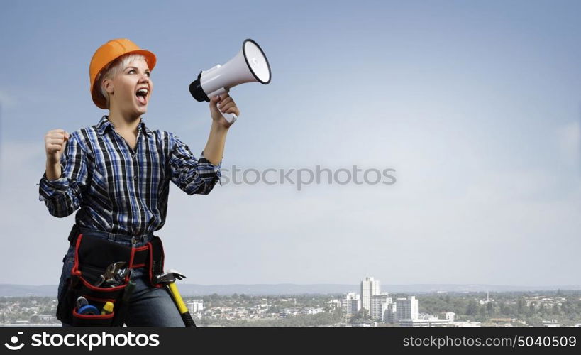 Woman builder with megaphone. Young emotional woman builder screaming in megaphone