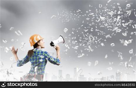Woman builder. Young woman builder in hardhat screaming in megaphone