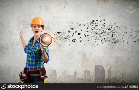 Woman builder. Young woman builder in hardhat screaming in megaphone